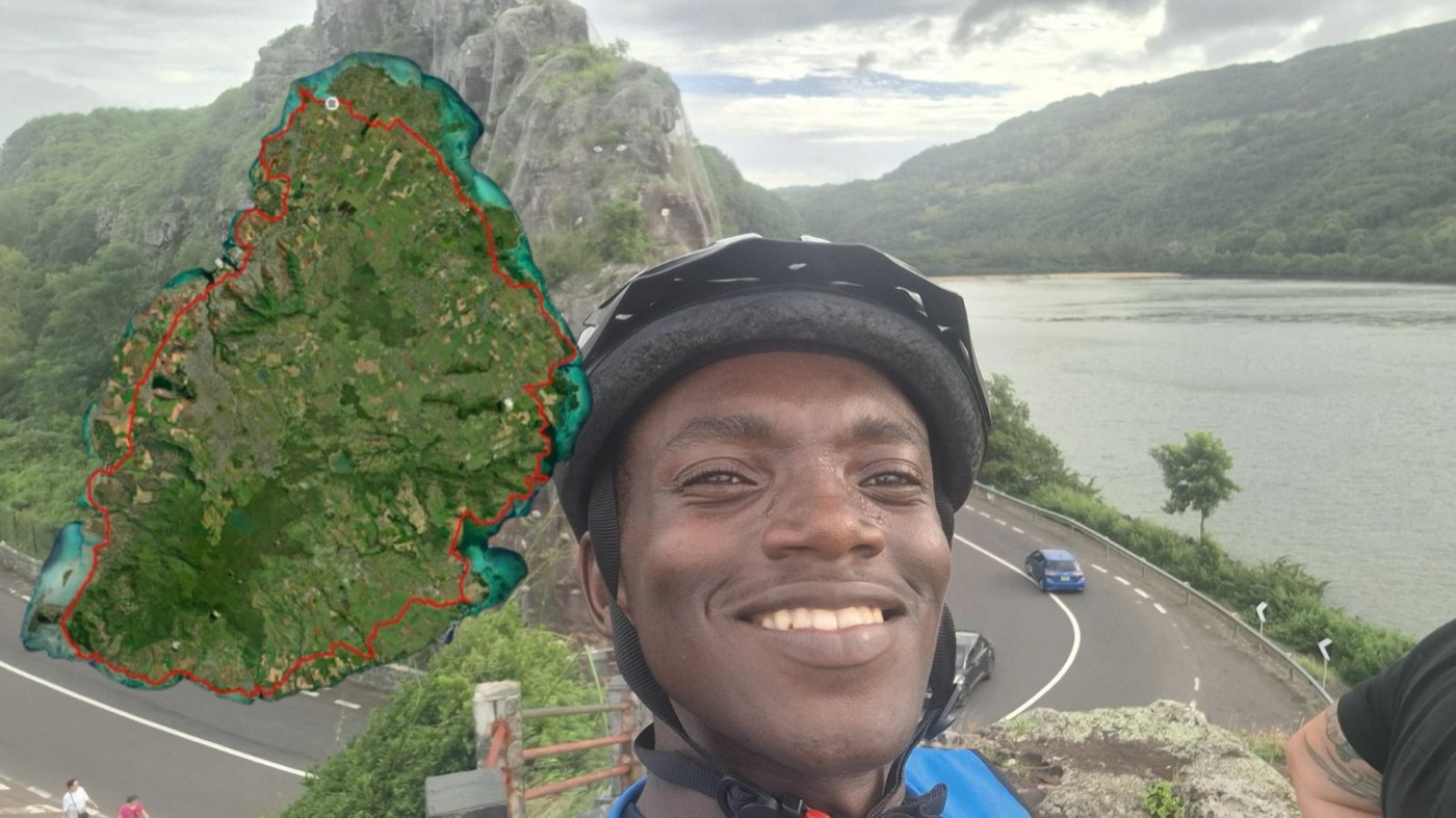 Pascal Gihozo on the Mauritius coastal road with a map of his island route